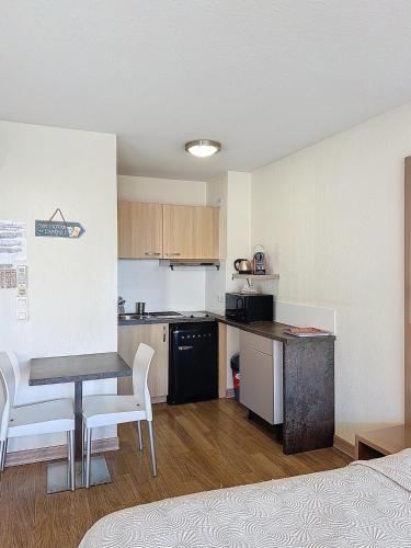 une petite cuisine avec une table et une table et des chaises dans l'établissement Beau studio bord de mer à Villeneuve Loubet French Riviera, à Villeneuve-Loubet