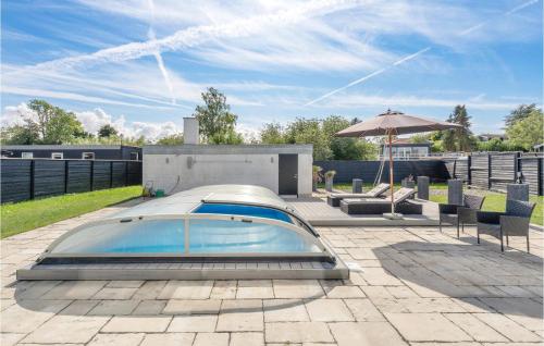 a swimming pool on a patio with an umbrella at 4 Bedroom Amazing Home In Strøby in Strøby