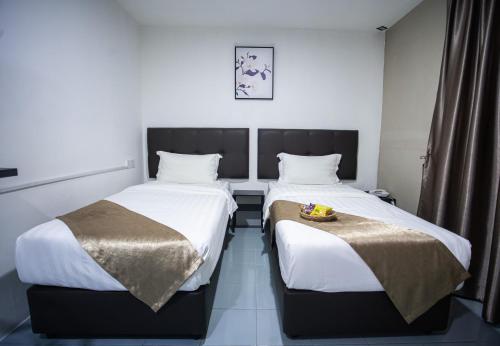 two beds in a hotel room with white sheets at Rex City Hotel in Johor Bahru