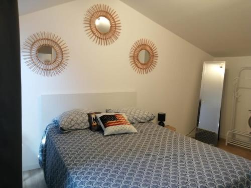 a bedroom with a bed and two mirrors on the wall at Maison de village sur Donzère in Donzère
