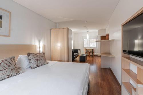 a bedroom with a large white bed and a kitchen at Dorrego Premium in Rosario