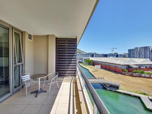 a balcony with a table and chairs and a pool at Birds-eye canal view - Walk to CTICC and V&A Waterfront! in Cape Town