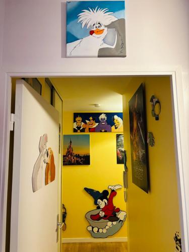 a hallway with a yellow wall with cartoon pictures at THE ENCHANTED HOUSE ( 15 min walk to Disney) in Serris