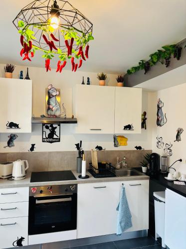 a kitchen with white cabinets and a chandelier at THE ENCHANTED HOUSE ( 15 min walk to Disney) in Serris