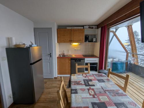 - une cuisine avec une table et un réfrigérateur dans la chambre dans l'établissement V du Bachat - A21 Arolles - Appart spacieux 8pers, à Chamrousse