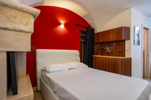 a bedroom with a white bed and a red wall at Giù in centro in Putignano