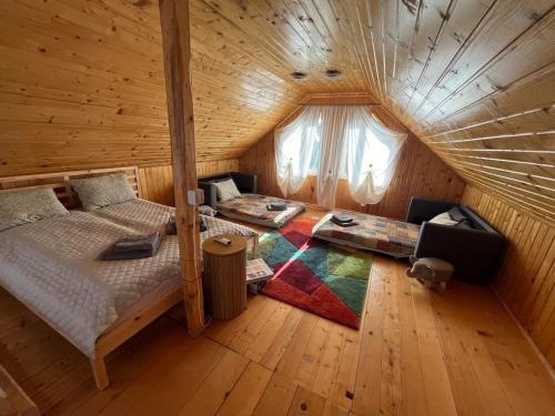 a bedroom in a log cabin with a bed and a couch at Căsuță la țară - liniște și viață rurală cotidiană in Cîrţa