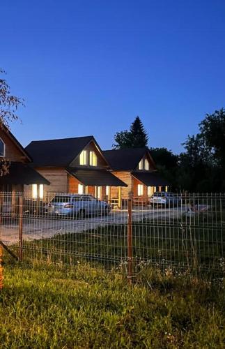 a fence in front of a house with cars parked at Căsuță la țară - liniște și viață rurală cotidiană in Cîrţa