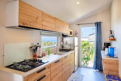 une cuisine avec des armoires en bois et un four à plaques de cuisson dans l'établissement Bungalow charmant à Saint-Raphaël, à Saint-Raphaël