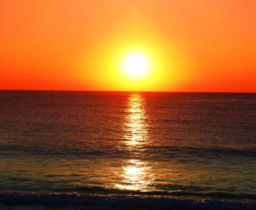 a sunset over the ocean with the sun setting at GranVista角島 in Oyama