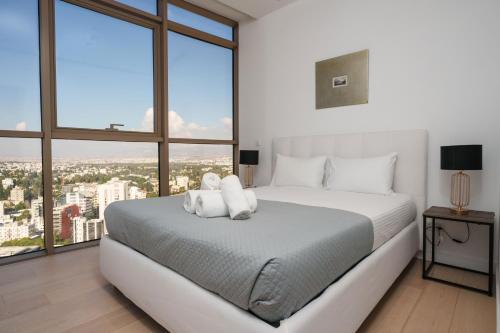 a bedroom with a large white bed with large windows at 360 Sky Residence, Gym & Pool - 26th Floor in Nicosia