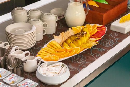 a table with a plate of fruit and a plate of milk at Metropol Hotel in Ferizaj