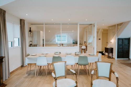 une salle à manger avec une table et des chaises blanches dans l'établissement Maison Vue Mer - Plage à Pied, à La Trinité-sur-Mer