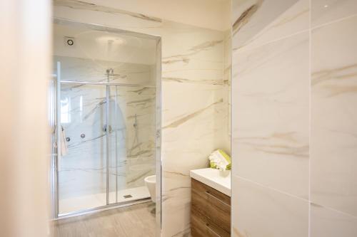 a white bathroom with a shower and a sink at Tramonto sul Lago in Passignano sul Trasimeno