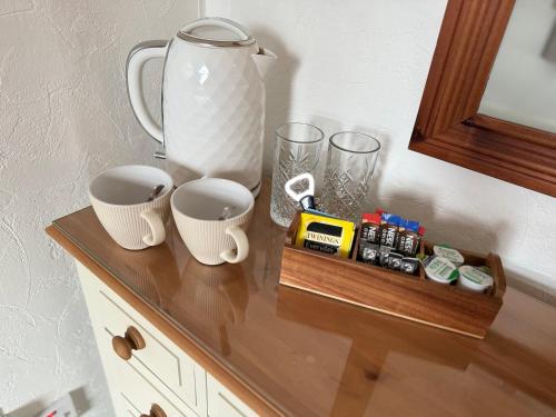a table with two cups and a vase on it at The Olivers Guest House in Hereford