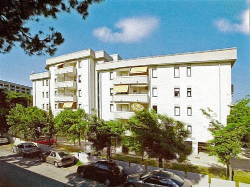a large white building with cars parked in a parking lot at Appartamenti Nasse in Bibione