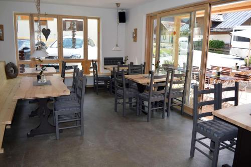 un restaurante con mesas y sillas de madera y ventanas en Bergsteiger-Hotel "Grüner Hut" en Bad Hindelang