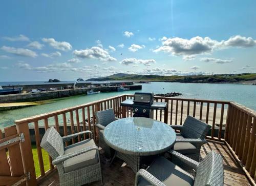 a deck with a table and chairs and a grill at Top Floor Retreat Portmor- Sea, Beach & Balcony in Slievebane