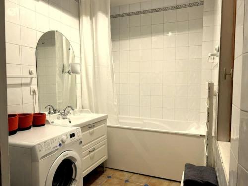 La salle de bains blanche est pourvue d'un lave-linge et d'une baignoire. dans l'établissement Appartement Capitole Daurade, à Toulouse
