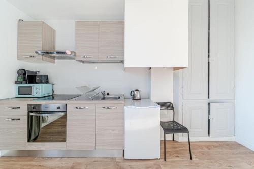 una cocina con armarios blancos y una silla negra en Maison Fontanières Studio Laurent 2 persons, en La Mulatière