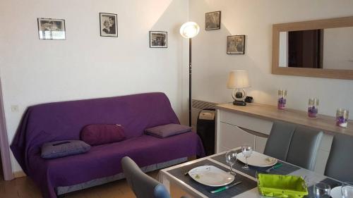 un salon avec un canapé violet et une table dans l'établissement Accès direct plage pour ce superbe T2 moderne et fonctionnel - 6FR325, à Saint Cyprien Plage