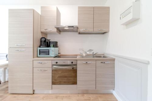 - une cuisine avec des placards en bois et un four micro-ondes dans l'établissement Maison Fontanières Le Mourguet Cosy - 2 People, à La Mulatière