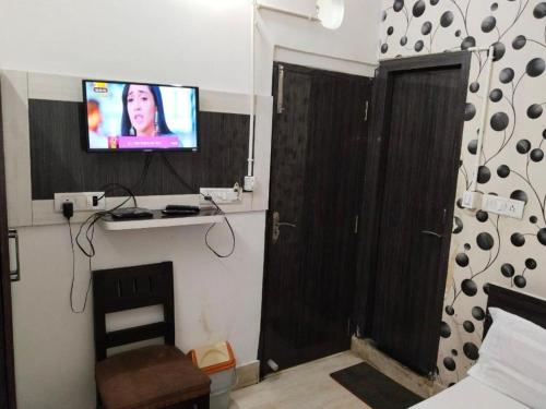 a room with a tv on a wall with a bed at Hotel Airlines in Kolkata