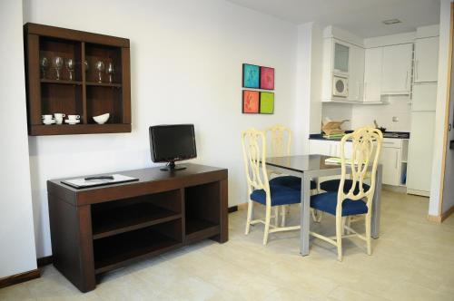 a kitchen with a desk and a table and chairs at Apartamentos Turisticos Noray in Argoños