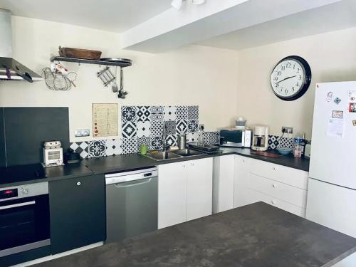 une cuisine avec des placards blancs et une horloge murale dans l'établissement Maison de vacances près de Plan-d'Aups-Sainte-Baume, à Plan dʼAups