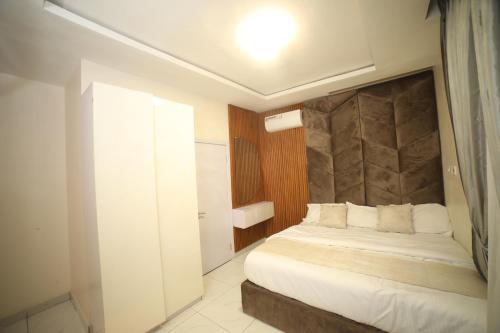 - une chambre avec un lit blanc et une tête de lit dans l'établissement Damac, à Ikuata