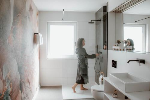 a woman standing in a bathroom with a shower at Boutique Hotel GreenLeaf in Sinzing