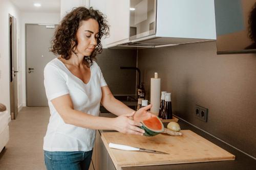 a woman standing in a kitchen holding a piece of watermelon at Boutique Hotel GreenLeaf in Sinzing