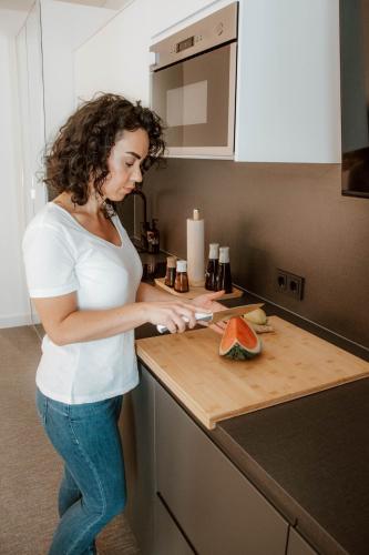 a woman standing in a kitchen cutting a piece of fruit at Boutique Hotel GreenLeaf in Sinzing