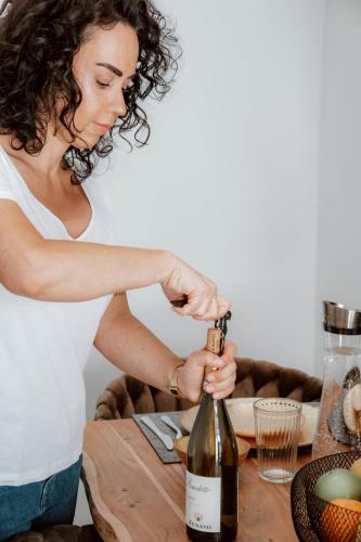 a woman opening a bottle of wine on a table at Boutique Hotel GreenLeaf in Sinzing