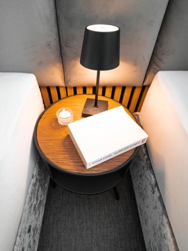 a table with a lamp and a book on it at Boutique Hotel GreenLeaf in Sinzing