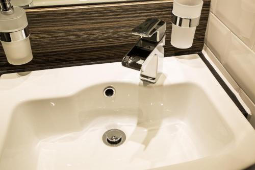 a white sink in a bathroom with two cups at Mondo Hotel in Coatbridge