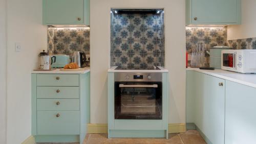 a kitchen with blue cabinets and a stove at Chequers Cottage in Coberley