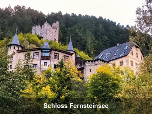 an old castle on top of a hill with trees at Schloss Hotel Fernsteinsee in Nassereith