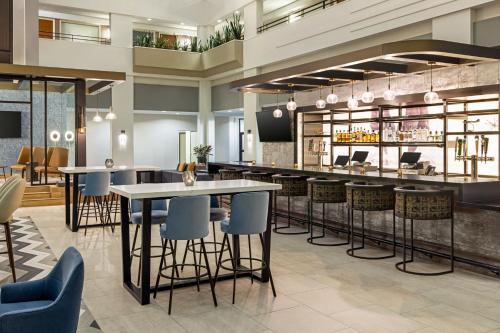 a lobby with tables and chairs and a bar at Sheraton Suites Chicago O'Hare in Rosemont