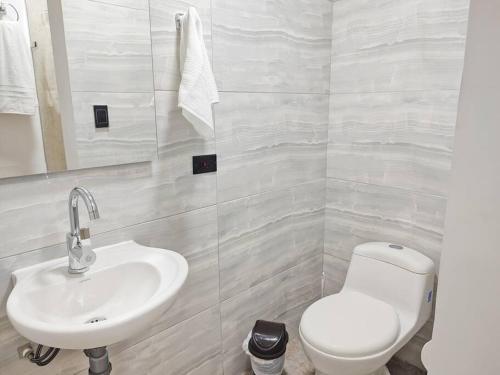 a bathroom with a white toilet and a sink at Cómodo apartamento en San Vicente - Cali in Cali