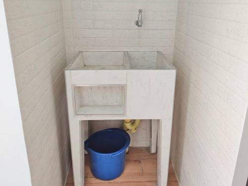 a bathroom with a white sink and a blue bucket at Cómodo apartamento en San Vicente - Cali in Cali