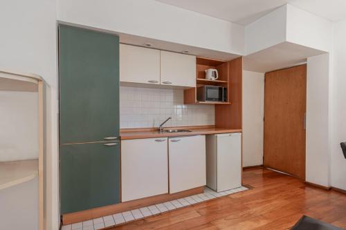 a kitchen with white cabinets and a green door at Dorrego Premium in Rosario