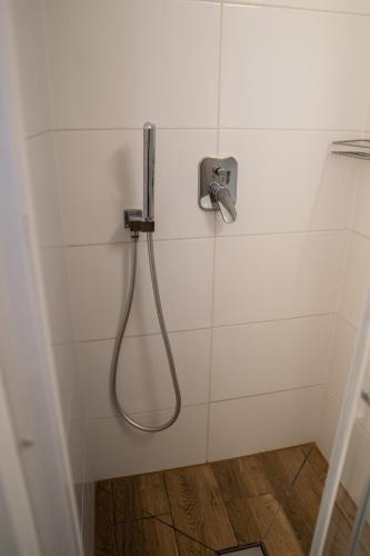 a shower with a hose in a white tiled bathroom at Zajazd w Biskupinie in Biskupin