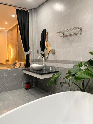 a bathroom with a sink and a mirror and a tub at Sea House Hotels and Apartments in Vung Tau