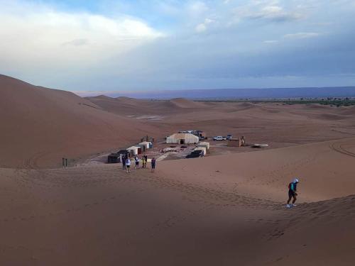 a group of people walking in the desert at Camp atlantic chegaga in Mhamid