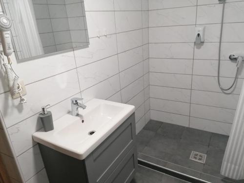 a white bathroom with a sink and a shower at Szépasszony Fogadó in Eger