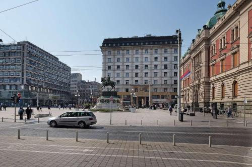 ein Auto, das eine Stadtstraße mit Gebäuden entlangfährt in der Unterkunft Paradise Museum City Center in Belgrad
