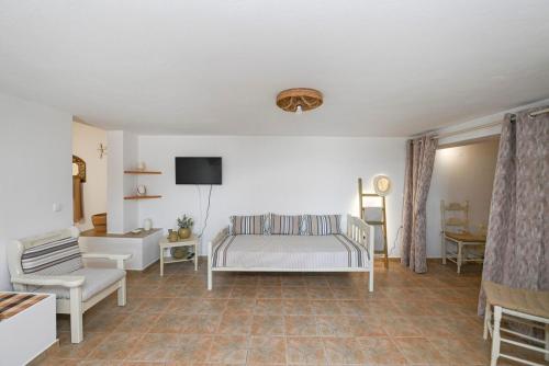 a bedroom with a bed and a chair and a tv at La Luna in Agia Barbara Tinos in Agios Sostis