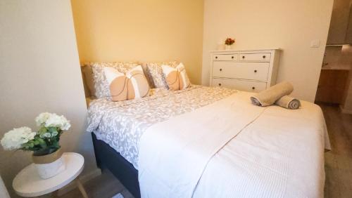 a bedroom with a white bed with a dresser and flowers at Modern Boho Charm in Kallio, Walk to City Center in Helsinki