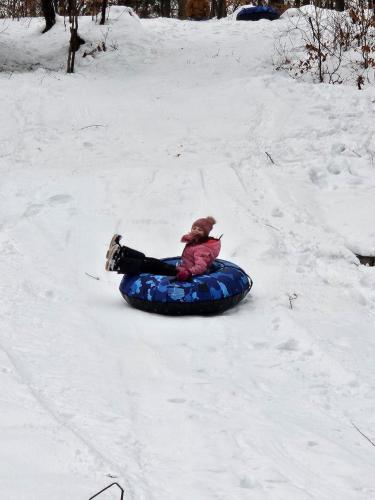 a child is sitting on a tube in the snow at paradis sauvage geronimo in St-Etienne de Bolton